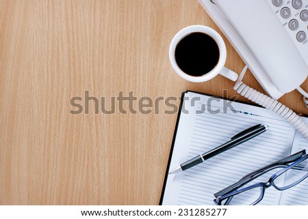 Cup of Black Coffee on the Wooden Table of Customer Service Officer with Notebook, Pen and Reading Glasses.