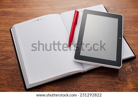 Close up Red Pen and Tablet Computer on Top of Open Clean Notes, Resting on the Wooden Desk with Copy Space for Text. Emphasizing Modern Way of Learning Concept.