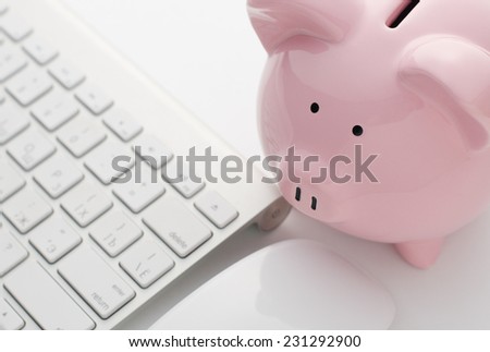 Close up Pink Piggy Bank and White Computer Keyboard on Top of White Blank Table. Emphasizing Saving Concept.