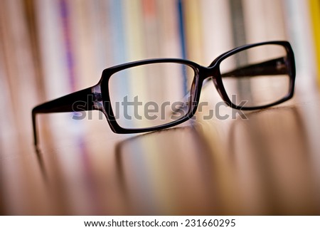 Close up Unisex Eyeglasses with Black Frame on Top of Wooden Table at the Office.