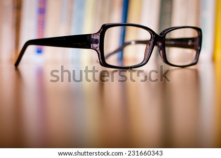 Close up Unisex Eyeglasses with Black Frame on Top of Wooden Table at the Office.