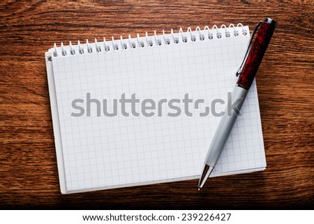 Close up Conceptual White Blank Graphing Notebook and Pen with Copy Space for Text. Resting on Brown Wooden Table.