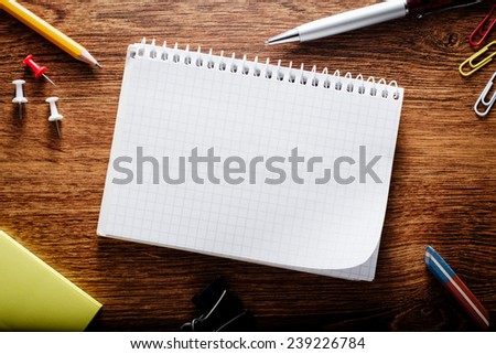 Close up Spiral Blank Graphing Notebook with Other School Supplies on Brown Wooden Table with Copy Space for Texts