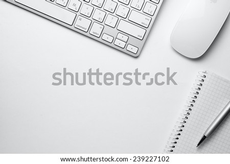 Conceptual White Ballpoint Pen, Clean Spiral Notes, Computer Keyboard and Mouse on Top of White Table with Copy Space at the Center.