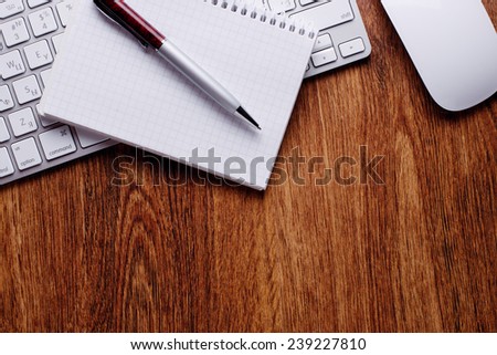 Conceptual Pen and Notes with Computer Keyboard and Mouse on Top of Wooden Table with Copy Space on Bottom.