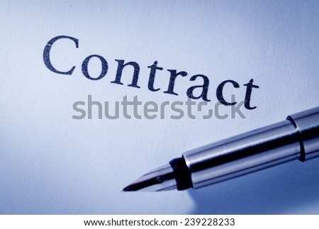 Close up overhead view of the nib of a fountain pen lying on a sheet of blank white paper headed - Contract