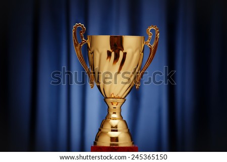 Golden glowing trophy cup on a dark blue background