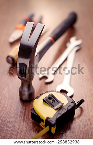 Close up Head of a Claw Hammer Hand Tool on Top of a Wooden Table with Other Hand Tools on the Sides