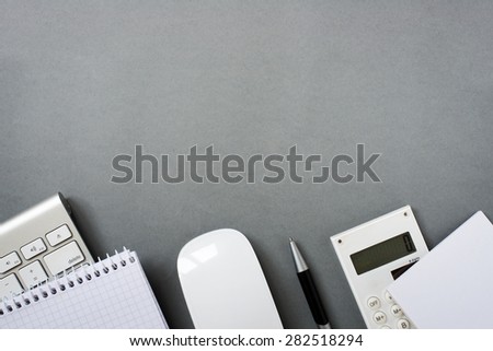 High Angle View of Mac Computer Keyboard and Mouse with Note Pads, Calculator and Pen on Grey Desk with Ample Copy Space