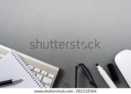 High Angle View of Mac Computer Keyboard and Mouse with Paper, Pen and Eyeglasses on Grey Desk with Ample Copy Space