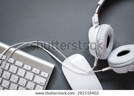 High Angle View of Modern White Audio Headphones with Cord, Mac Computer Keyboard and Mouse on Grey Desk Background with Copy Space