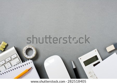 High Angle View of Mac Computer Keyboard and Mouse with Various Office Supplies Scattered on Grey Desk with Ample Copy Space