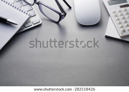 Angled View of Mac Computer Keyboard and Mouse with Various Office Supplies on Grey Desk with Ample Copy Space