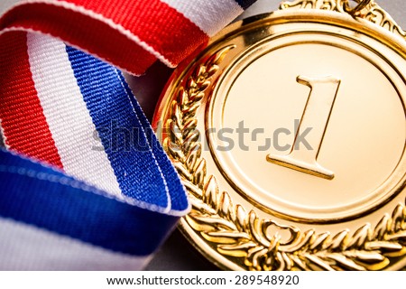 Gold medal in the foreground on three-colour ribbon