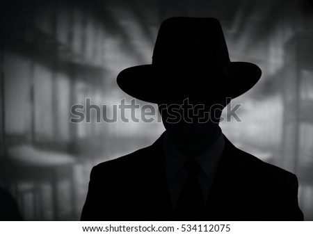 Silhouette of a mysterious man in a vintage style wide brimmed hat in a close up black and white head and shoulders portrait