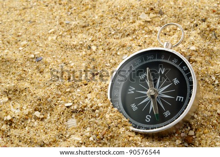 compass on the sea-sand with patches of light on glass