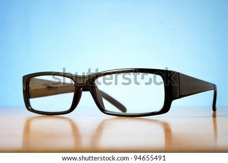 black-rimmed glasses on a table and a blue background