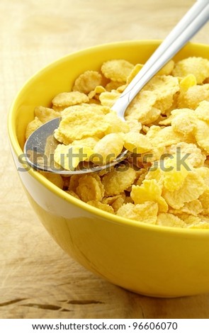 corn flakes in a yellow bowl and a spoon