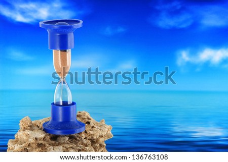 sand-glass or hour-glass placed on the rock with sea background
