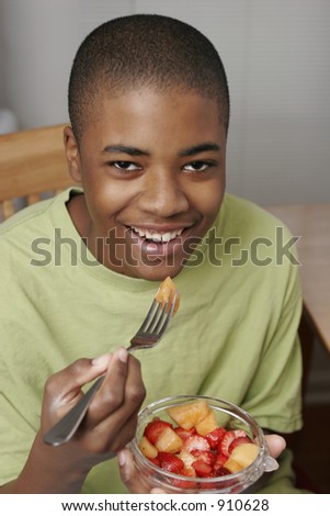african american male teen eating fruit in bowl