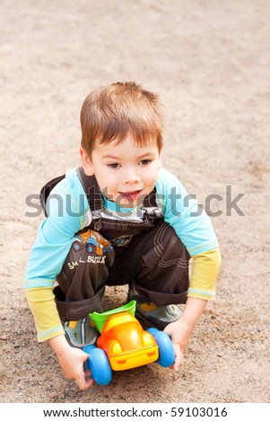 a little boy smiling and playing in the toy car in the children's village on a summer day