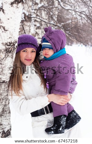 mother  keeps a small child in her arms. A walk in the snowy winter park.