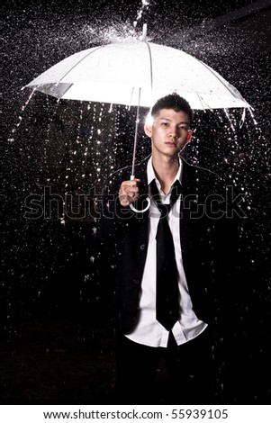 Asian man wearing suit holding  a white umbrella in the rain dark.