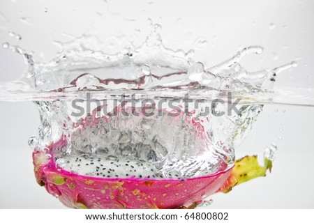 Exotic Dragon fruit dropped into water isolated on white.