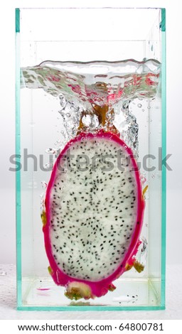 Exotic Dragon fruit dropped into water glass isolated on white.