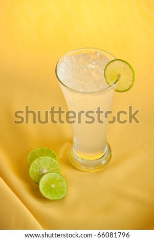 Refreshing lemonade with  a slice of lemon isolated on yellow fabric background.