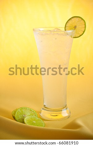 Refreshing lemonade with  a slice of lemon isolated on yellow fabric background.