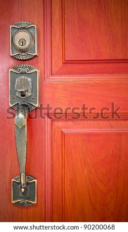 Old brass handle on orange wood door.