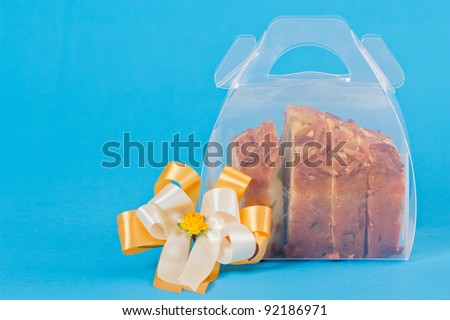 pound cake in Christmas package  and yellow white ribbon Isolated on blue background.
