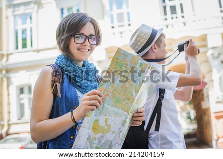 Trendy young couple in town with touristic map