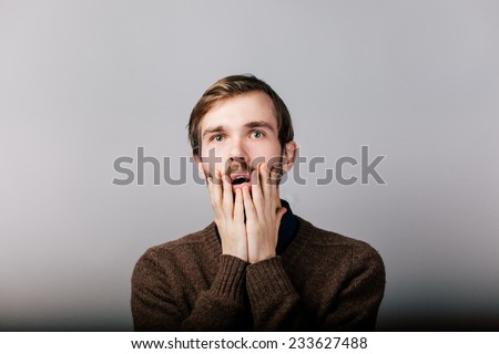 young man with beard in brown sweater in shock