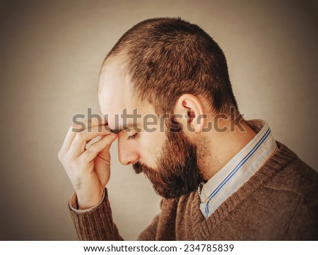 man with a beard in brown sweater sad about troubled deep thought