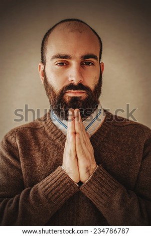praying man with a beard in brown sweater