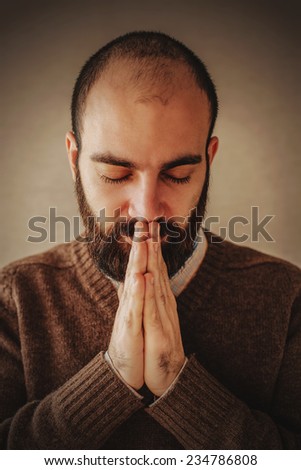 praying man with a beard in brown sweater
