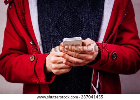 Smiling young man looking at his smart phone while text messaging