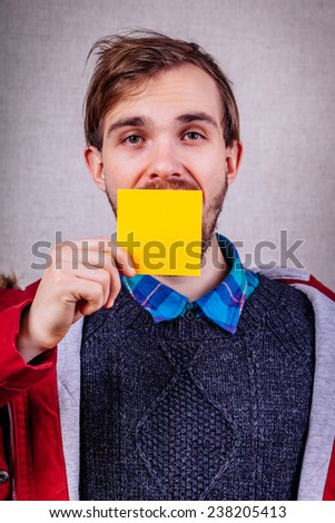 Closeup portrait of young man with a piece of paper covering his mouth