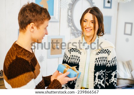 Young man hands a gift box to his girlfriend