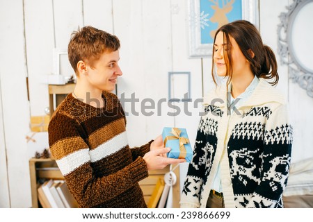 Young man hands a gift box to his girlfriend