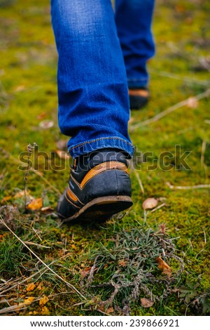 Person wearing walking shoes takes a step on a mountain hiking path, closeup photo.