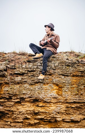 Handsome romantic guitarist play music siting on beach rock.
