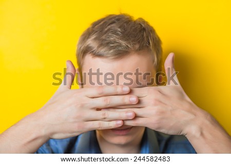 Young man in a blue shirt on a yellow background. showing fatigue, sleepy, sleepy, closes his eyes with his hands. gesture. photo shoot.
