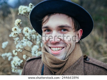 Portrait of a smiling young man in warm clothing shivering while having a walk in forest on a winter day