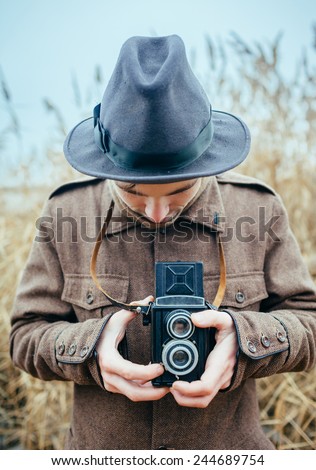 Man hand holding retro photo camera outdoor Lifestyle concept with  autumn nature on background