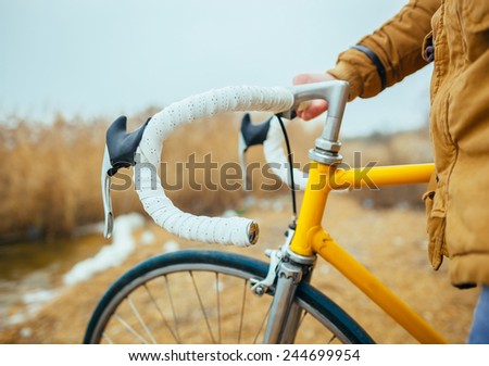a young man with hands on the steering wheel of bicycle near the lake