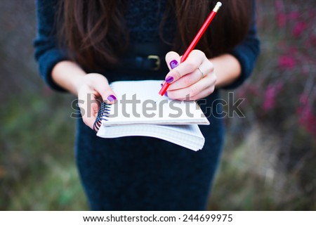 girl on nature writing in a notebook
