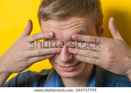 Closeup portrait of young guy, man, student, boy, worker, employee,  closing eyes with hands, can\'t see, hiding, isolated on yellow background. See no evil concept. Human emotions facial expressions